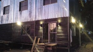 Una cabaña de madera rústica con un porche, una puerta y una ventana.