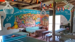 Una habitación con mesa de ping pong, bancos de madera y un mural colorido en la pared.
