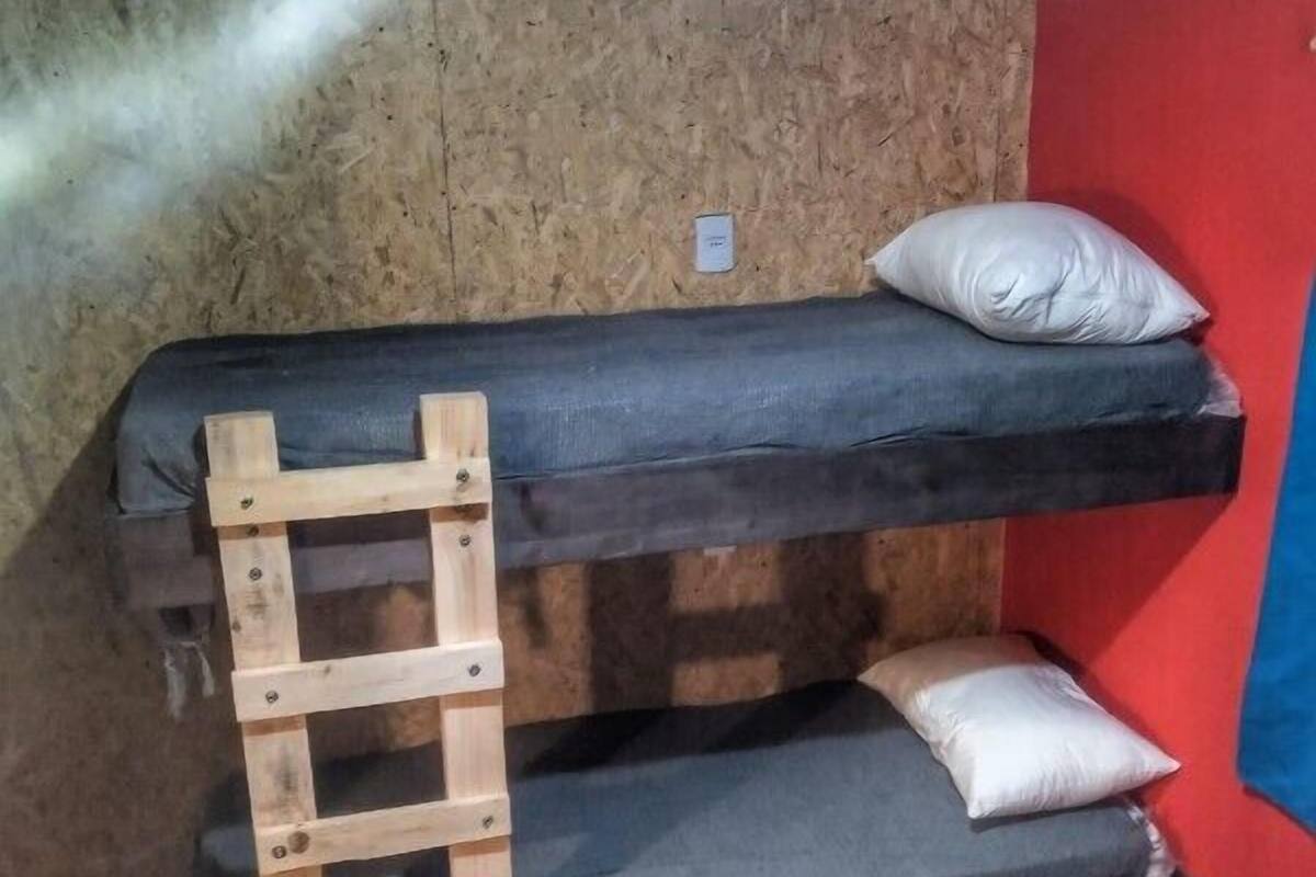 A bunk bed with a wooden ladder, two pillows, and a red wall.