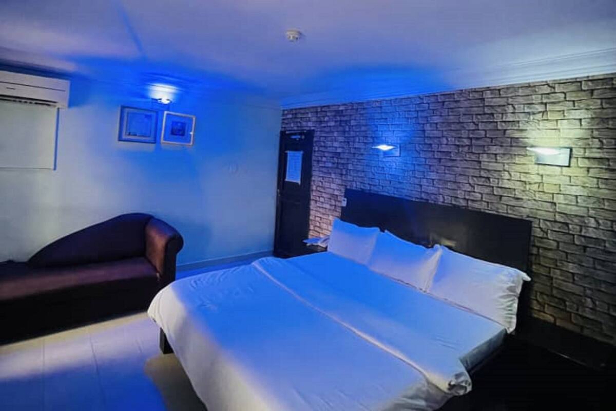Ein Schlafzimmer mit einem großen Bett, einem dunkelgrauen Sofa und einer Wand mit Backsteinmuster.