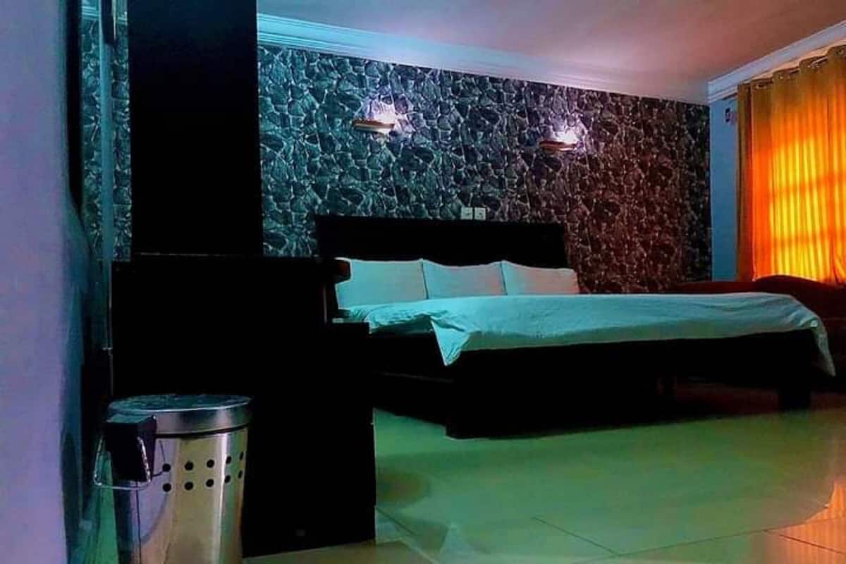 Ein Schlafzimmer mit einem Bett, einem Mülleimer und einer Wand mit Steinmuster.