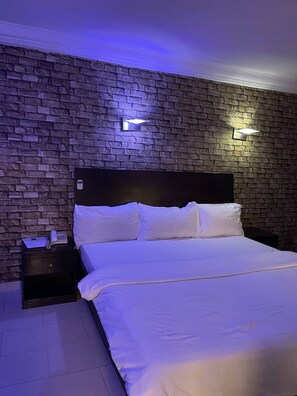 Une chambre avec un mur décoré d’un motif en briques, une tête de lit en bois et deux lampes de chevet.