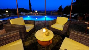 A poolside area with wicker furniture and a table with a candle. - Villa Favola - Stunning private villa with pool (Fabbrica)