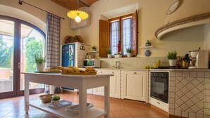 A kitchen with white cabinets, a tiled backsplash, a built-in oven, and a dining area with a table and chairs. - Villa Favola - Stunning private villa with pool (Fabbrica)