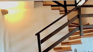 A staircase with wooden steps and black handrails, leading to a landing with a wooden cabinet and a vase. - Villa Gesine with private pool and sea views (Massa Lubrense)