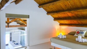A modern bedroom with a wooden ceiling, a bed with white linens, and a bedside table. - Villa Garofano - Coastal villa with pool (Marsala)