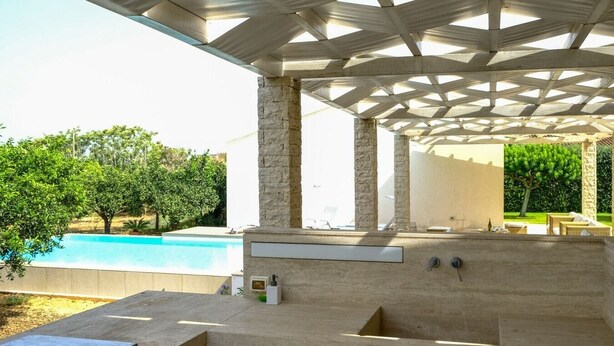 An outdoor kitchen area with a pool in the background. - Villa Garofano - Coastal villa with pool (Marsala)