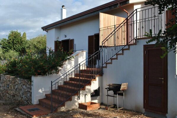 A two-story house with a staircase, a barbecue grill, and a stone wall. - Villa Itri (Panorama) - Apartment with shared pool (Itri)