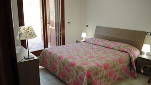 A bedroom with a bed, two bedside tables, a lamp, and a window with blinds. - Villa Itri - Whole Villa (Itri)