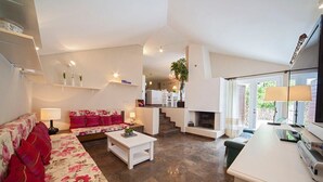 A spacious living area with a sofa, coffee table, and a fireplace. There is a kitchen area with a dining table and chairs. - Villa Ziva - Modern villa with pool, Dalmatia (Brela - Krug)