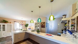 A modern kitchen with a white countertop, hanging pendant lights, and a built-in wine rack. - Villa Ziva - Modern villa with pool, Dalmatia (Brela - Krug)