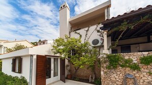 A modern house with a stone wall, a wooden door, and a small tree. - Villa Ziva - Modern villa with pool, Dalmatia (Brela - Krug)