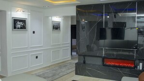 A modern living room with a fireplace, white paneling, and a large TV.