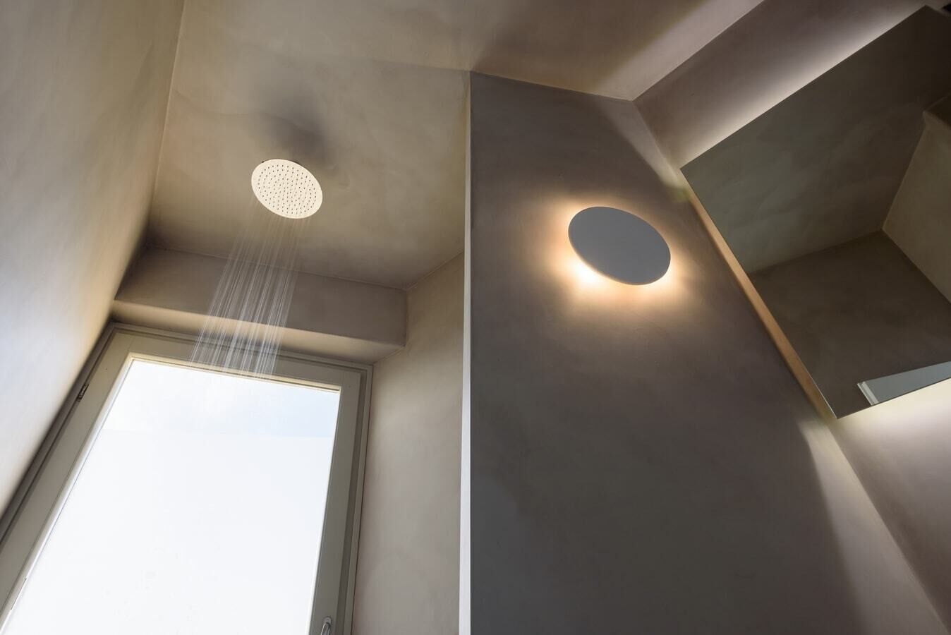 Une salle de bain moderne dotée d’un puits de lumière, d’un luminaire circulaire et d’un espace douche.