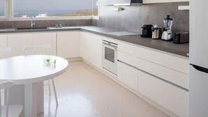 Eine moderne Küche mit weißen Schränken, einem Einbauofen, einer Spülmaschine und einem Fenster mit Blick auf eine schöne Aussicht.