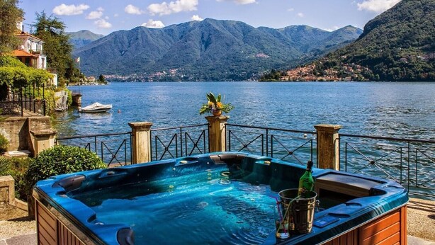 A hot tub with a mountain view, a wooden deck, and a railing. - Villa Vanessa - Luxurious waterfront private villa (Moltrasio)
