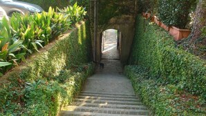 A stone staircase leading to a covered area, surrounded by lush greenery and a car parked nearby. - Villa Vanessa - Luxurious waterfront private villa (Moltrasio)