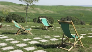 Two wooden lounge chairs with green cushions on a grassy lawn with a view of rolling hills. - Villa Sarta - Tuscan country villa with private pool (Pienza)
