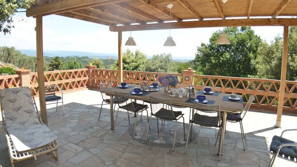 An outdoor patio with a wooden pergola, stone flooring, and a table set for dining. - Villa Pontedera - Countryside cottage with private pool (Capannori)