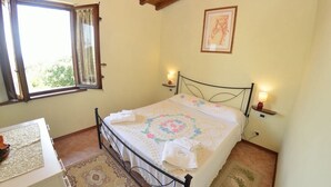 A bedroom with a bed, a desk, a chair, a window, and a wall-mounted picture. - Villa Pontedera - Countryside cottage with private pool (Capannori)