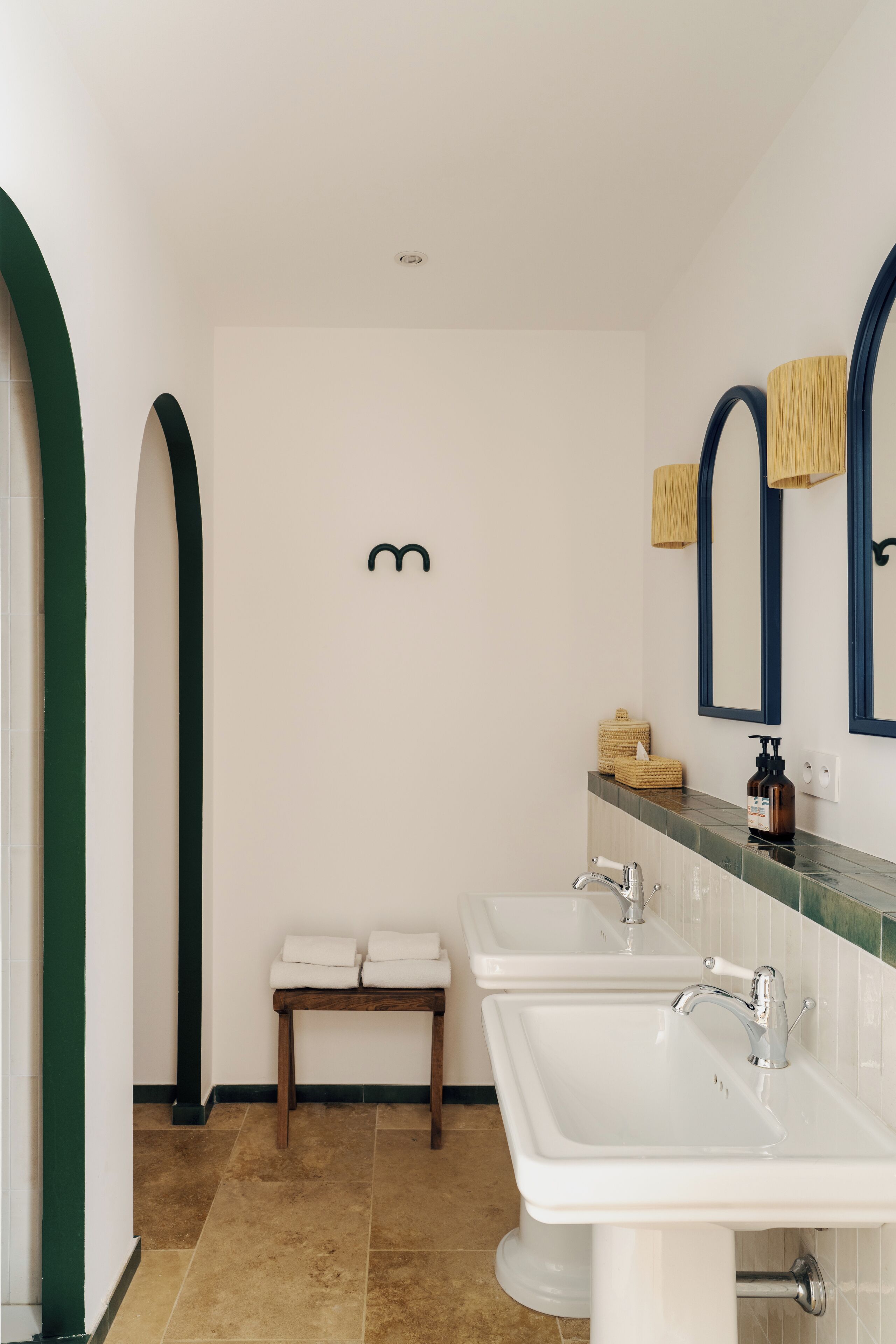 Une salle de bain moderne avec deux lavabos, un banc et un miroir.