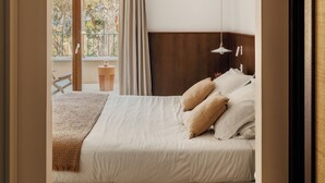 A bedroom with a bed, a wooden headboard, a hanging light fixture, and a view of the outdoors through a glass door.