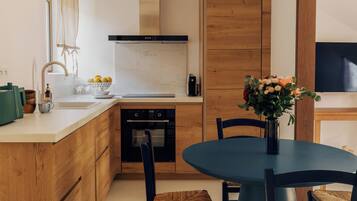 A modern kitchen with wooden cabinets, a central island, a round dining table with chairs, and a hanging light fixture.