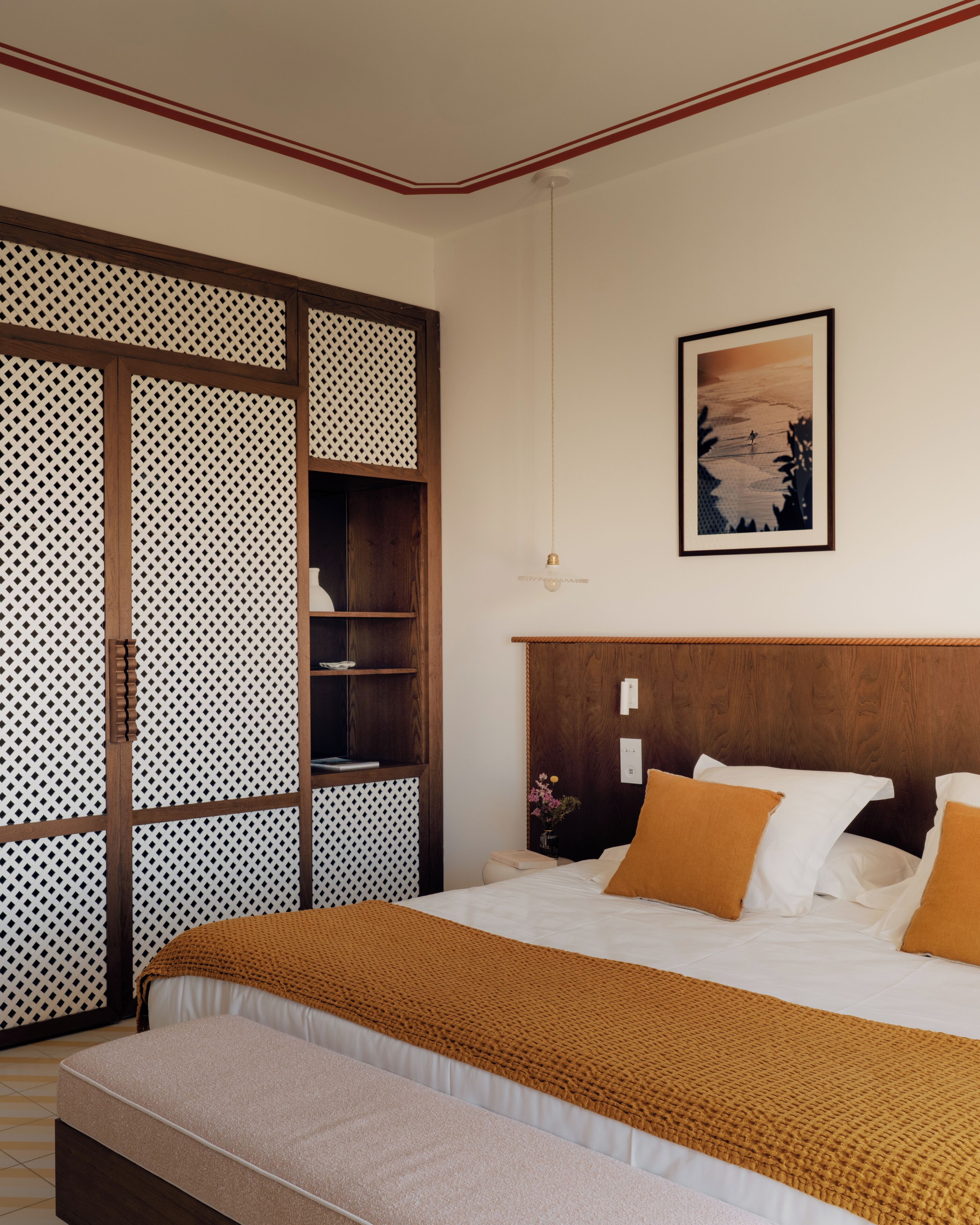 Quarto bem arrumado com uma cama, cabeceira de madeira, um quadro na parede e um painel decorativo.