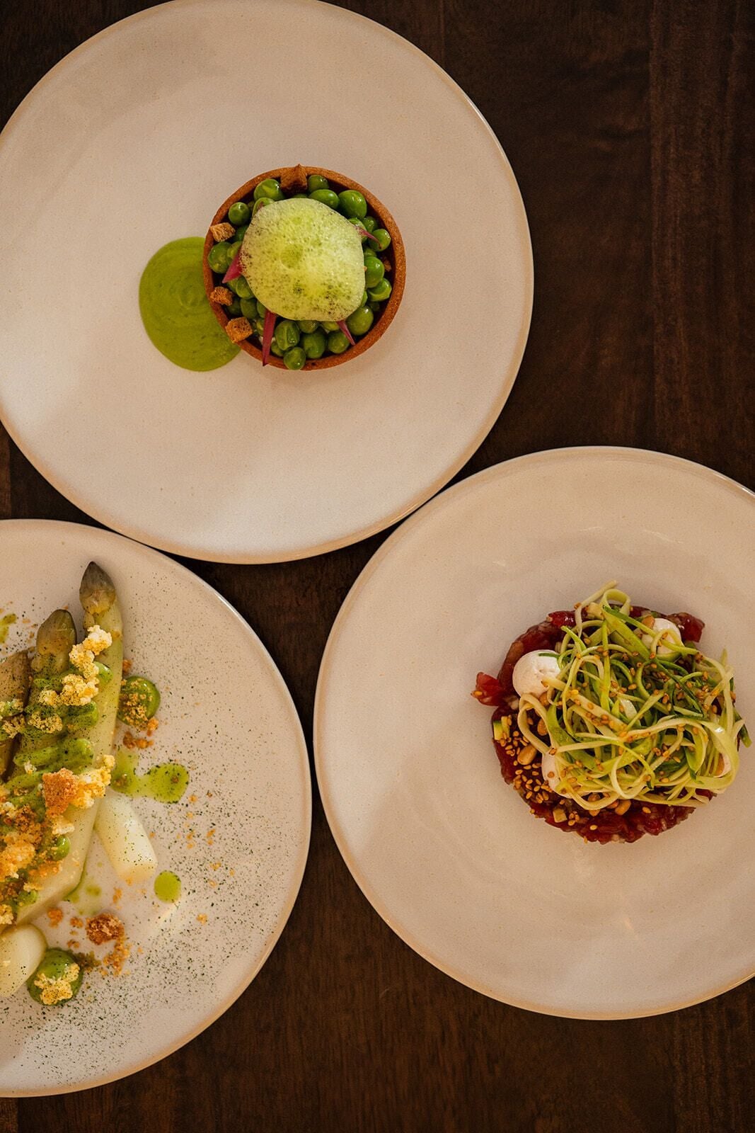 Three plates of food on a wooden table.