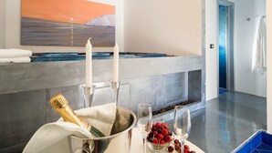 Ett modernt badrum med ett stort badkar, en tavla som föreställer en solnedgång och en flaska champagne.
