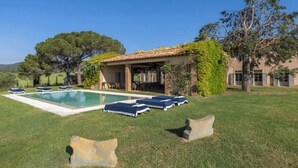 A pool with lounge chairs, a covered patio, and a stone sculpture in a grassy area. - Villa Melissa - Stunning Tuscan Villa With Pool (Roccastrada)