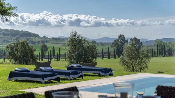 A poolside dining area with lounge chairs and a table set for a meal, overlooking a grassy landscape with trees and hills. - Villa Melissa - Stunning Tuscan Villa With Pool (Roccastrada)