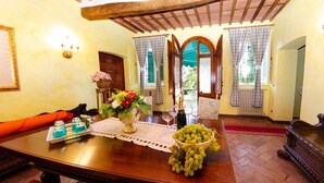 Un comedor con una mesa de madera, un jarrón de flores, un cuenco de uvas y una botella de champán.