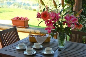 A wooden table with a floral arrangement, a basket of pastries, and several white cups and saucers. - Villa Maria - Countryside villa with a private pool (Magliano Sabina)