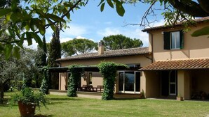 A two-story house with a tiled roof, a covered patio with outdoor furniture, and a well-maintained lawn. - Villa Maria - Countryside villa with a private pool (Magliano Sabina)
