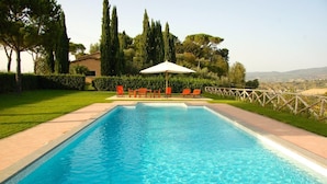 A rectangular swimming pool with clear blue water, surrounded by a paved deck. There are four orange lounge chairs and a white umbrella in the background. - Villa Maria - Countryside villa with a private pool (Magliano Sabina)