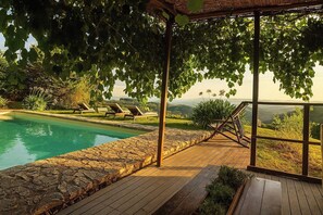 A poolside area with a pergola, lounge chairs, and a view of the landscape. - Villa Luisa - Farmhouse with private pool (Certaldo)