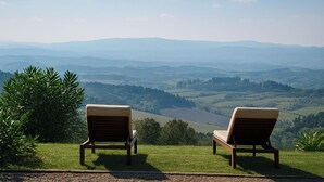 Zwei Holzliegen mit Blick auf sanfte H ügel und ein Tal.