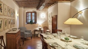 Ein Esszimmer mit Holzbalkendecke, einem für vier Personen gedeckten Tisch und gerahmten Pflanzenbildern an den Wänden.