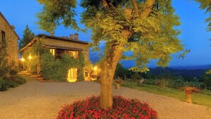 Ein Gebäude aus Stein mit Efeu, einer Schotterauffahrt und roten Blumen im Vordergrund.