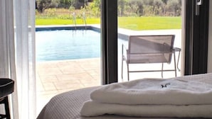 Et værelse med en stor skydedør, der fører til en pool, og en stol udenfor.
