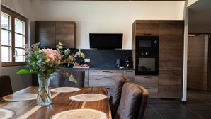 Een moderne keuken met donkere houten kastjes, een ingebouwde oven en een flatscreen televisie.