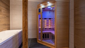 Een sauna met een houten buitenkant, glazen deuren, een bedieningspaneel en een bankje van binnen.