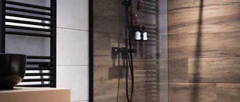 A modern bathroom with a wooden wall, a black towel rack, and a shower area.