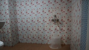 A bathroom with floral patterned tiles, a shower, and a toilet. - Hotel Sikara Kumbakonam (Kumbakonam)