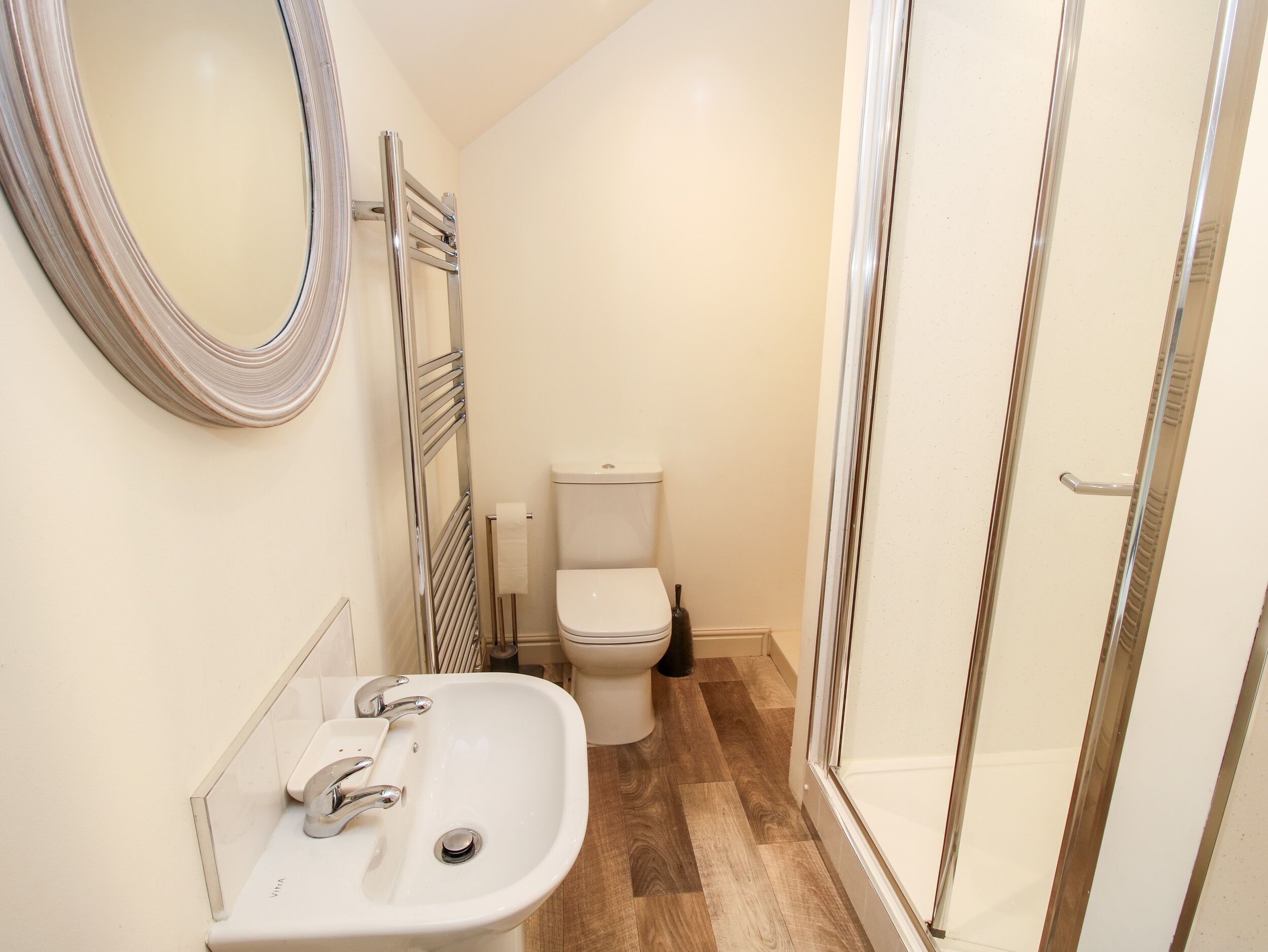 A bathroom with a white sink, mirror, toilet, and shower area.