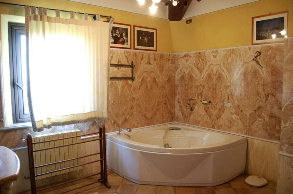 Une salle de bain avec une baignoire sur pieds, un radiateur, un porte-serviettes et une fenêtre avec des rideaux.