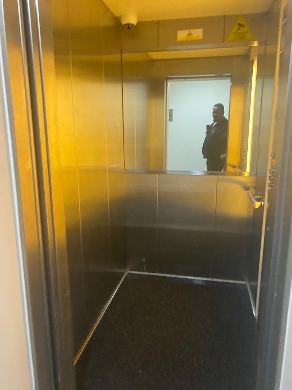A narrow elevator with metallic walls and a reflective surface.