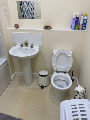 Bathroom features a pedestal sink, toilet, and mirror with geometric pattern.