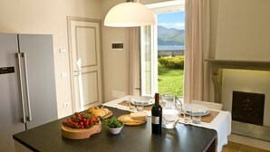 Une cuisine avec une table à manger dressée pour deux personnes, une bouteille de vin et une vue sur un lac.